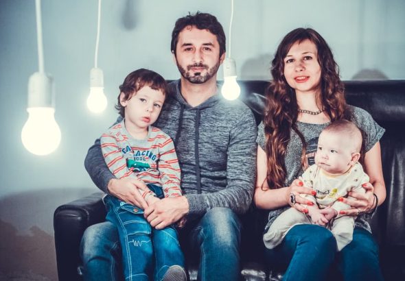A loving family portrait with parents and children sitting together in a modern, well-lit room.