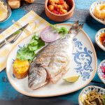 A vibrant Mediterranean meal featuring grilled fish and assorted appetizers on a rustic table.