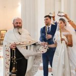 A traditional wedding ceremony with priest, bride, groom, and guests inside a church.